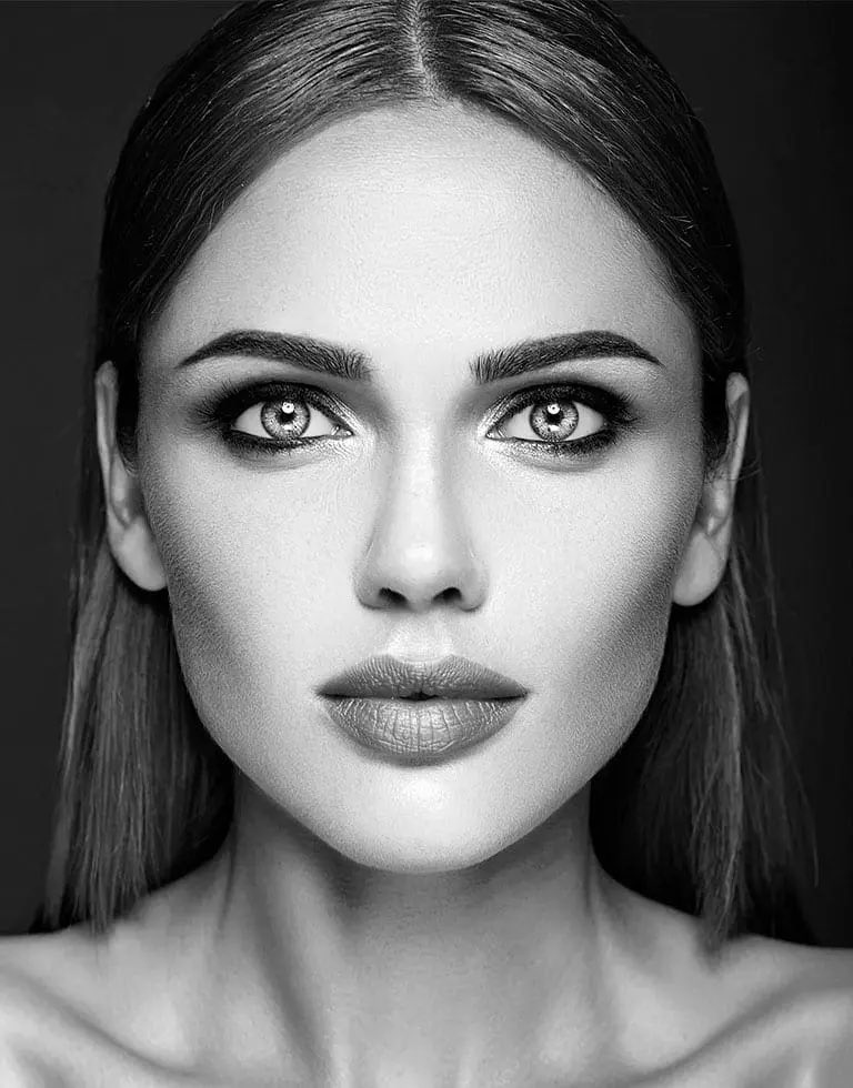 Black and white studio portrait, square to the camera and evenly lit, against a dark background.